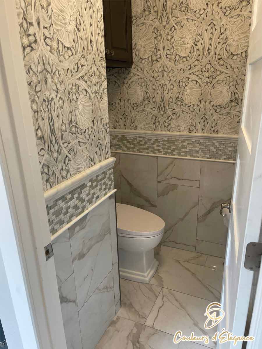 A residential bathroom water closet featuring beautiful wallpaper and tile.