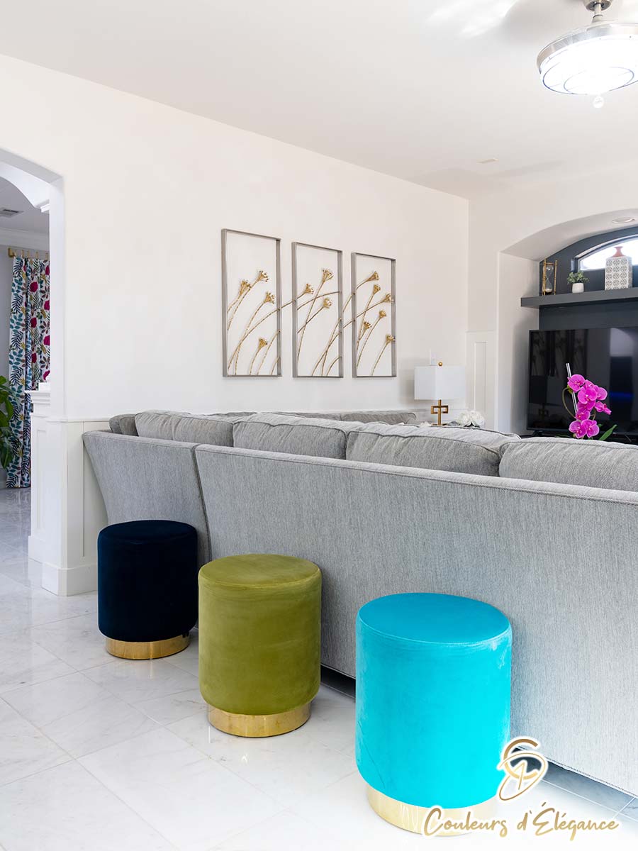 Colorful stools lined behind a grey couch.