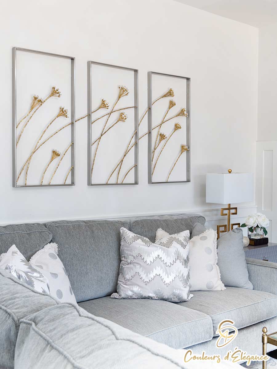 Wire flower artwork hangs on the wall over a grey couch.