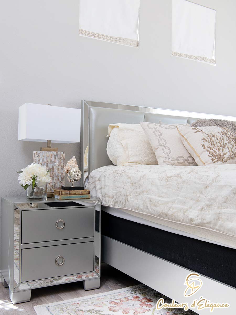 A mirrored nightstand next to a bed with a matching headboard.