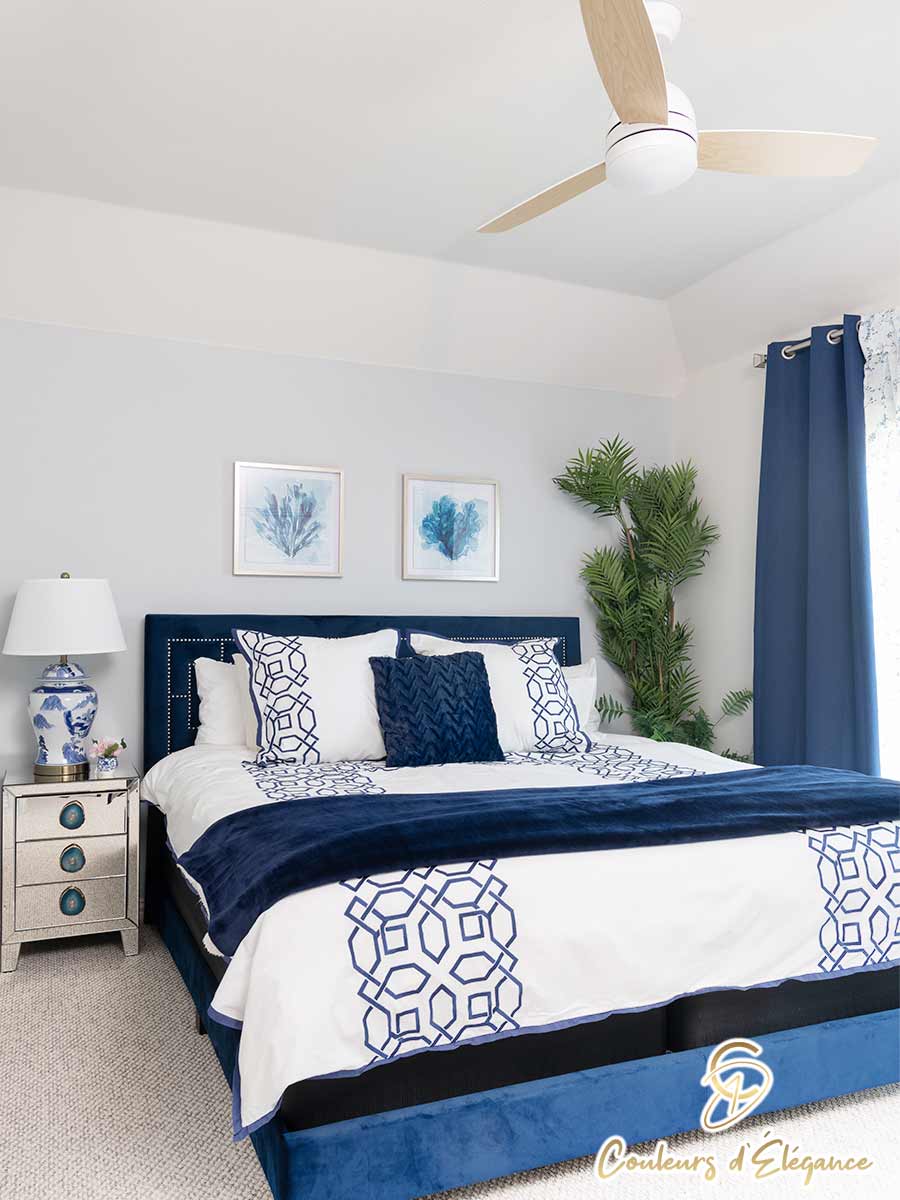 A mirrored nightstand next to a bed with a blue fabric headboard.