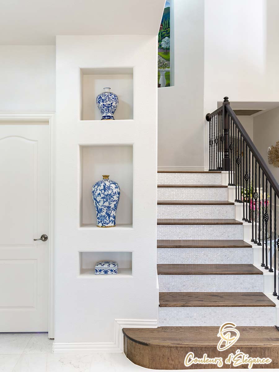 A beautiful staircase leading up to a painted archway with inset shelves at the bottom.