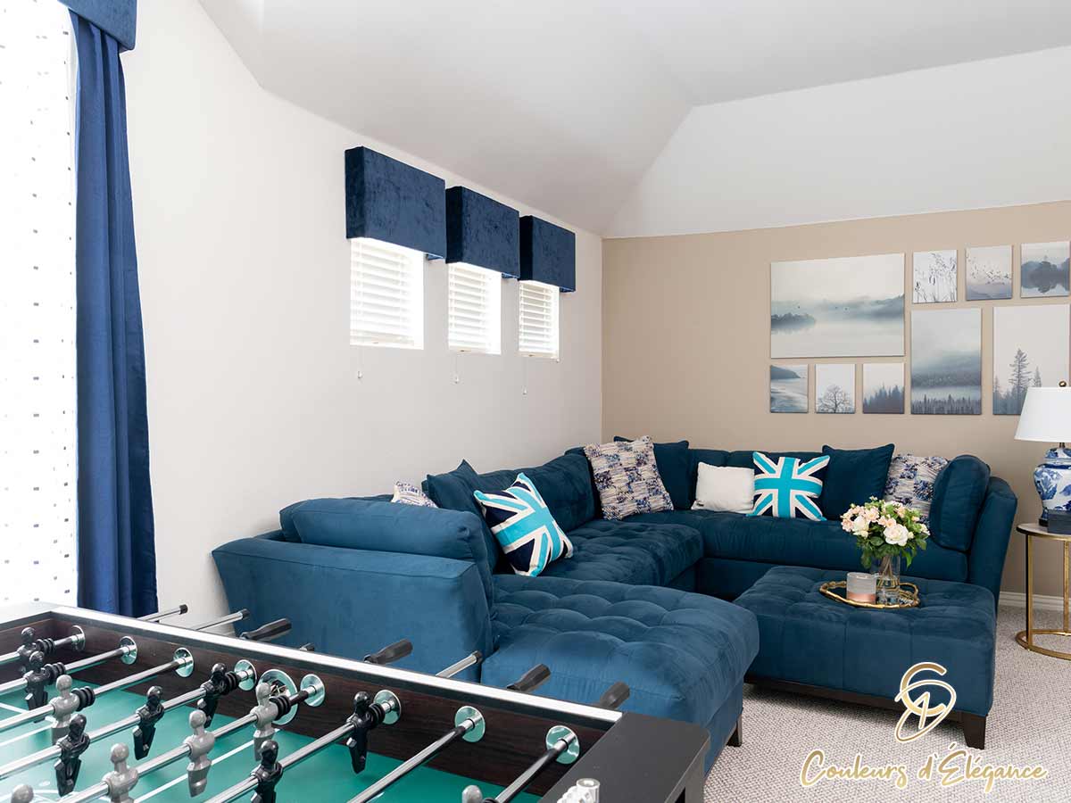 A foosball table in a room with a blue couch and ottoman.